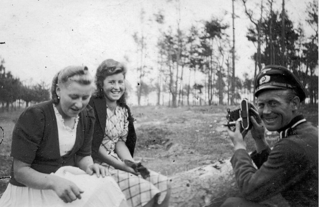A Wehrmacht soldier photographing two young Polish women. His comrades are calling him. Collection: Hans Citroen